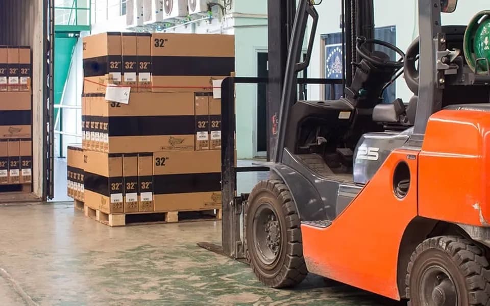 A forklift beside pallets of cartons in a warehouse