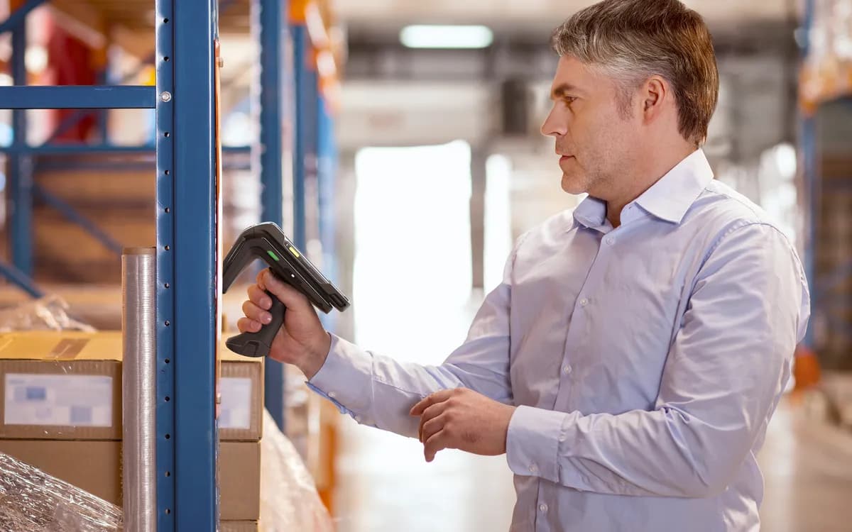 A worker counting stock on a shelf with a Zebra RFID handheld reader