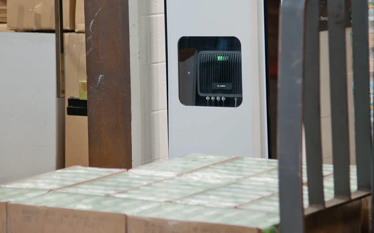 A Zebra fixed RFID reader beside a dock door, above a pallet of cartons