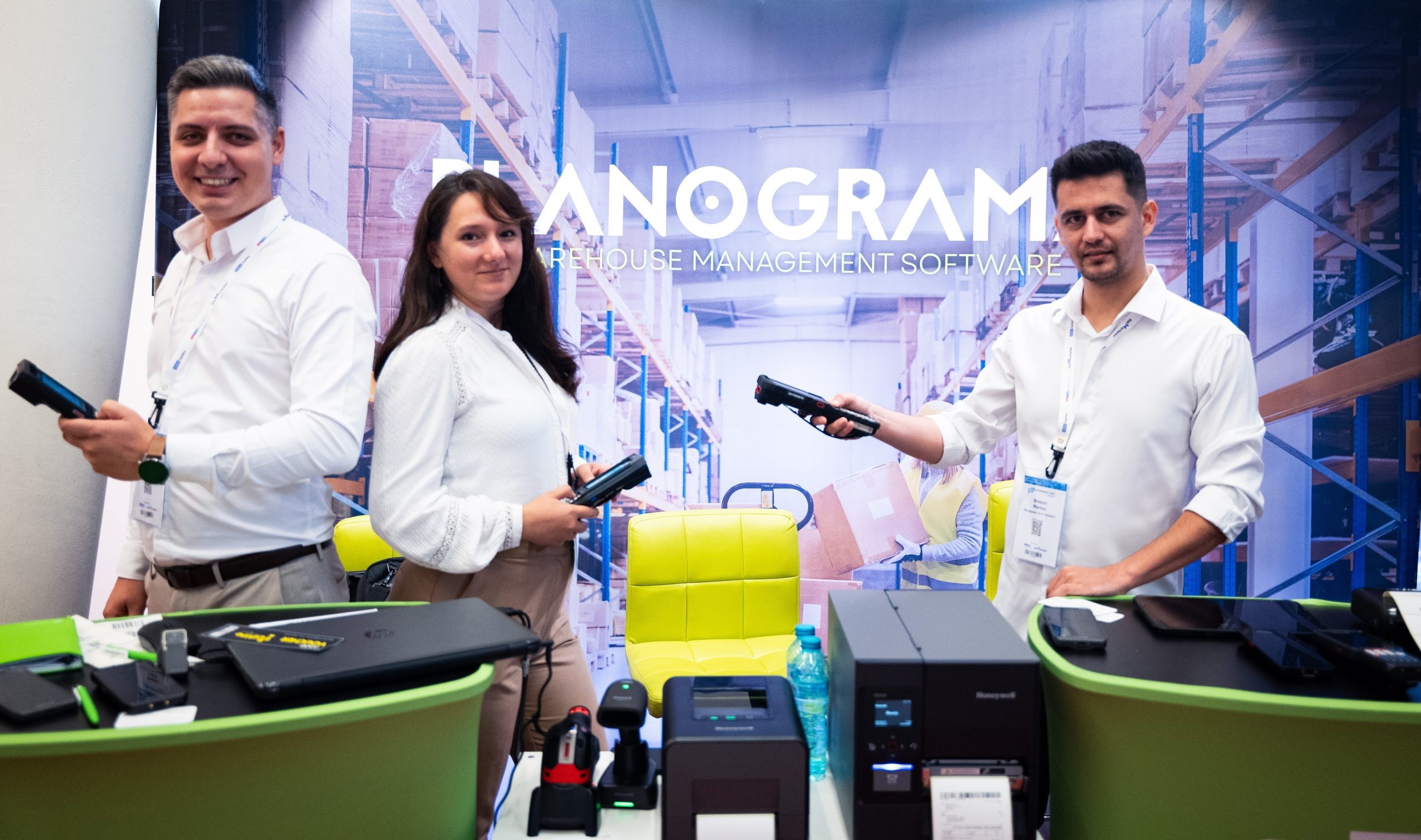 Drei Personen betreuen den Planograma-Stand bei den eCommerce Talks und halten mobile Handheld-Computer in den Händen, auf dem Tresen stehen Etikettendrucker und Barcode-Scanner von Honeywell